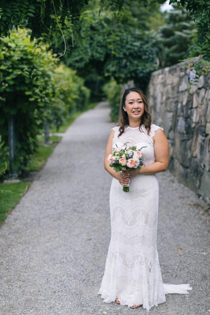 Veronica smiling with bouquet and wedding dress at Arnold Arboretum