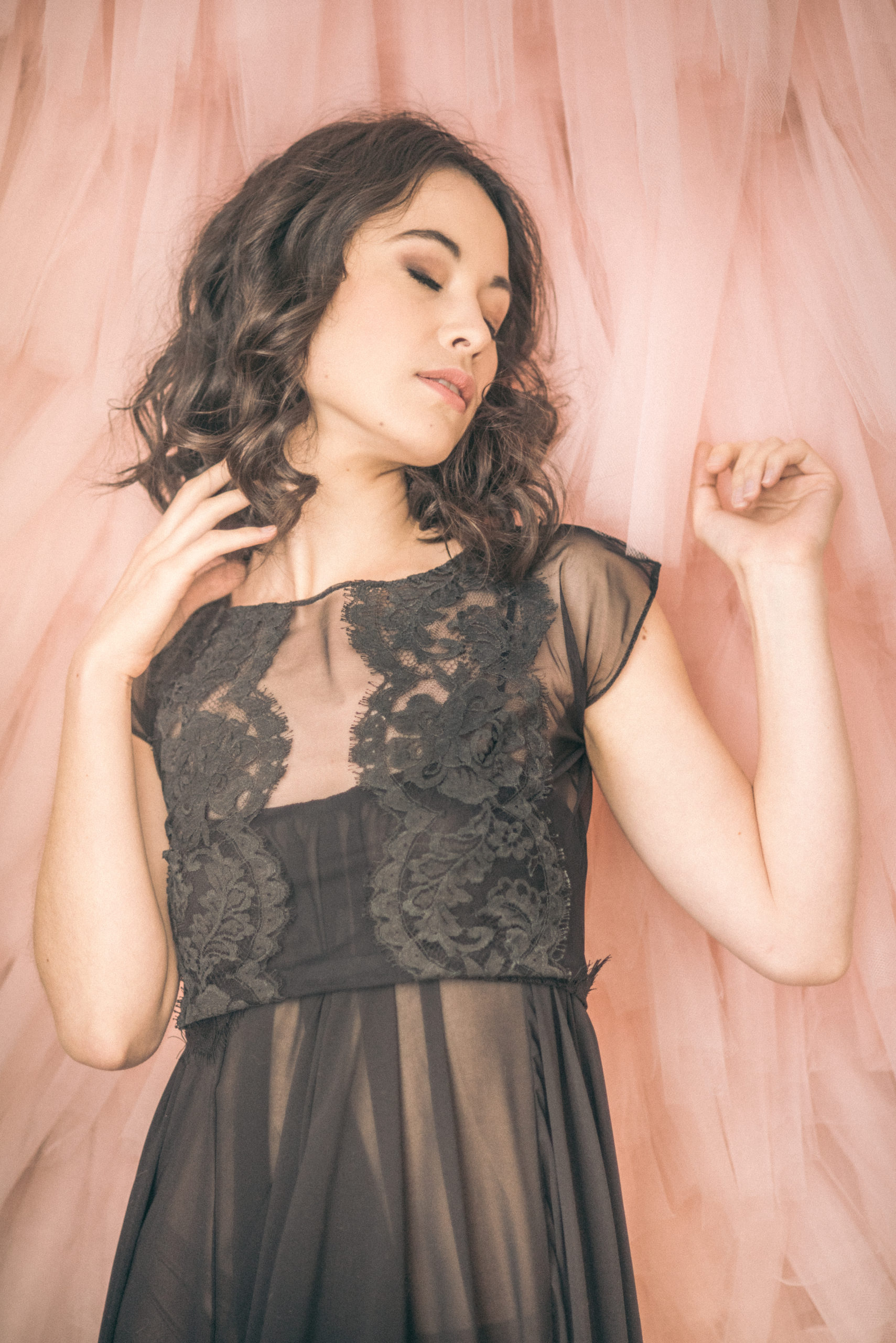 Maya boudoir shoot in black lace dress on pink tulle wall
