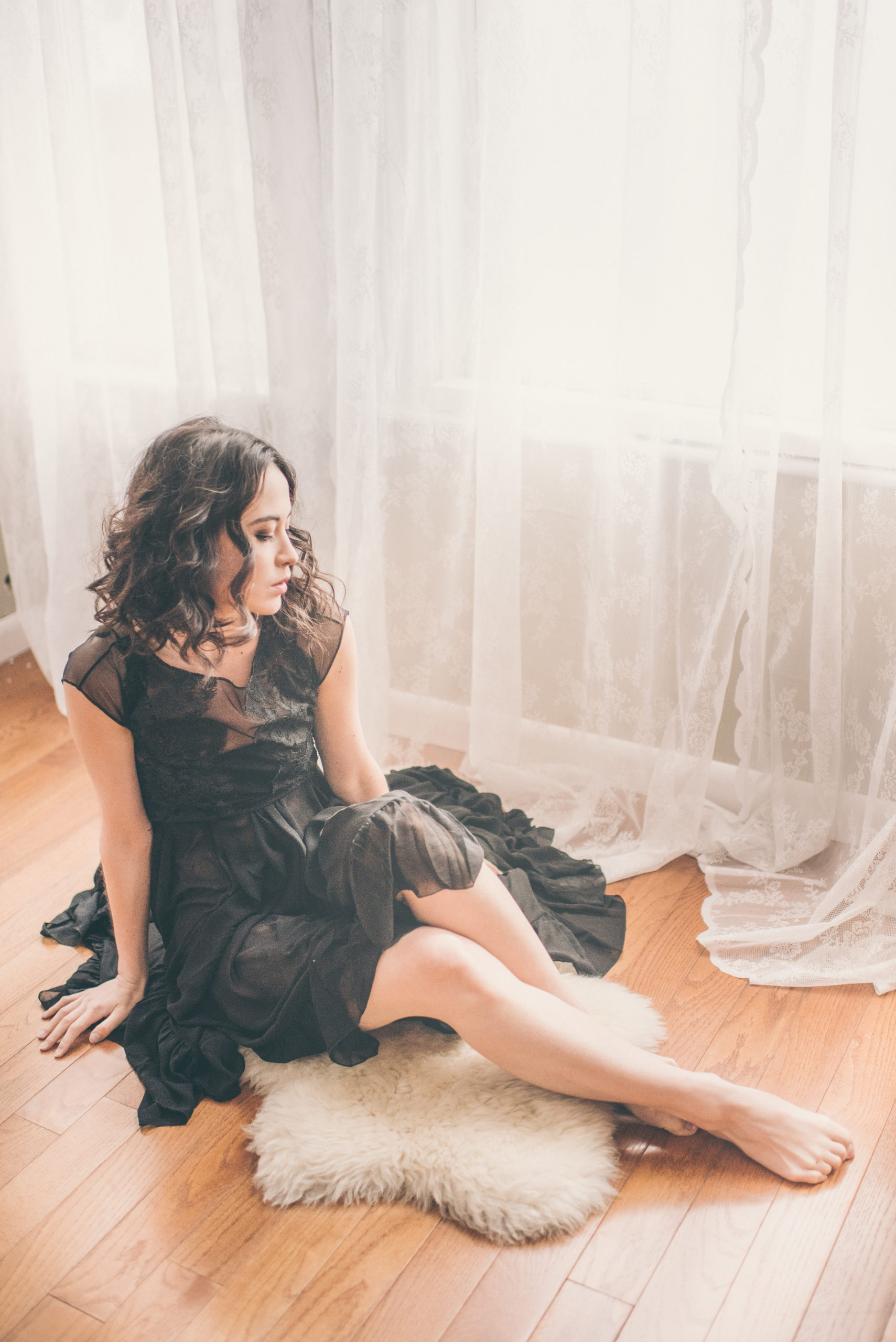 Maya boudoir shoot in black lace dress sitting on floor
