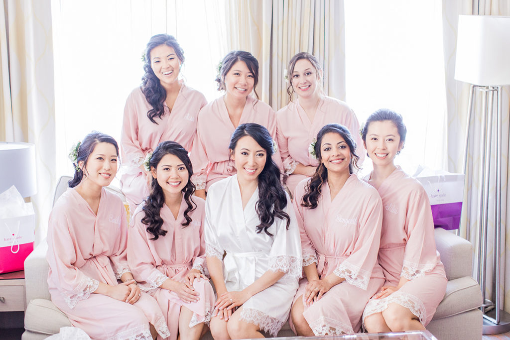 Chelsey and bridesmaids smile at hotel in pink robes